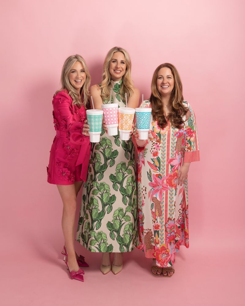 Three women holding social butterfly disposable foam colorful cups against a pink background